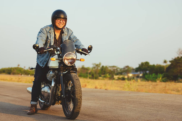 Motosikletli genç adam asfalt yolda motosiklet sürüyor, motosikletli adam özgürdür. - Fotoğraf, Görsel