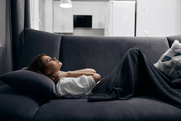 γυναίκα καλυμμένη με κουβέρτα αναπαύεται ξαπλωμένη στον καναπέ - Φωτογραφία, εικόνα