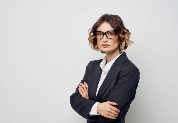 Una mujer de negocios en gafas y en un traje sobre un fondo claro cruzó sus brazos sobre su pecho - Foto, imagen