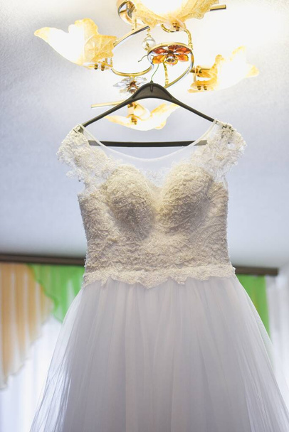Das Brautkleid hängt am Kronleuchter.  - Foto, Bild