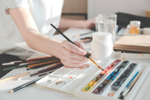Mujer pintando un cuadro con un pincel. Aprender a dibujar en casa. Autor Creando concepto de contenido. - Foto, imagen