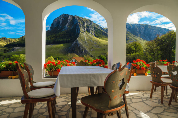 Majestueuse terrasse fleurie avec chaises et tables ornementales. Vue admirable depuis le balcon du restaurant avec Piatra Secuiului montagnes, Rimetea, Transylvanie, Roumanie, Europe - Photo, image