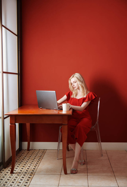 Молода доросла жінка сидить за столом і працює на ноутбуці
 - Фото, зображення