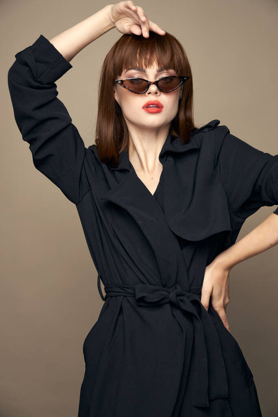 Stylische Frau hält die Hand über dem Kopf und an der Taille eine dunkle Brille - Foto, Bild