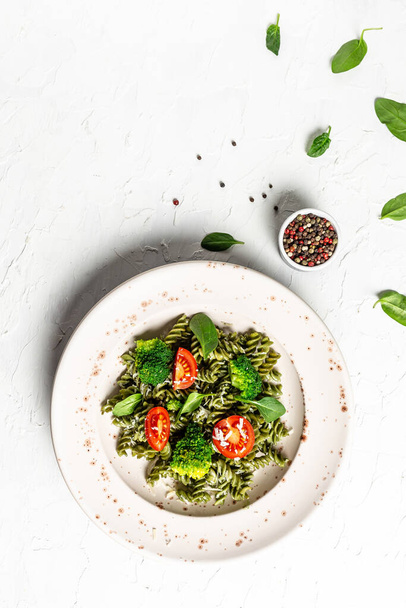 Pasta pesto vegan bowl. green pasta with spinach with cherry tomatoes. vertical image, place for text. top view. - Photo, Image
