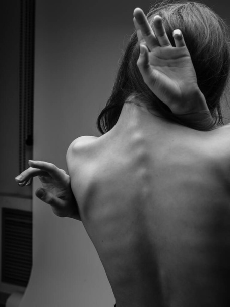 Zwart-wit foto van een lang haar model aanraken van zichzelf met de handen - Foto, afbeelding
