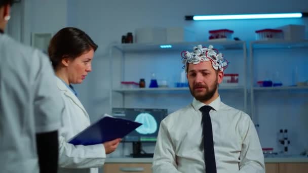 Onderzoeker neuroloog vraagt mans symptomen het nemen van notities op klembord - Video
