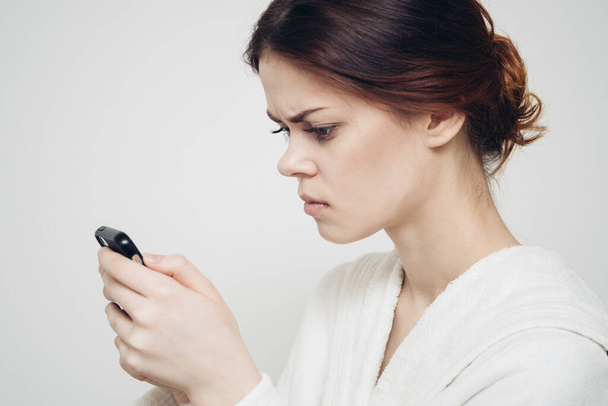 femme avec un téléphone portable tient une éponge dans sa main sur un fond clair - Photo, image