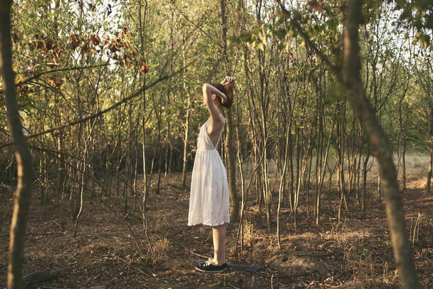Eine Frau im weißen Kleid geht in vollem Wuchs durch den Wald - Foto, Bild