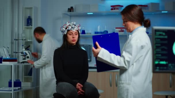 Naukowiec wskazując na schowek wyjaśniający leczenie choroby mózgu - Materiał filmowy, wideo