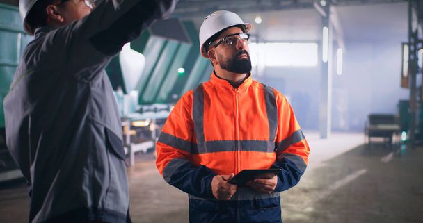 Άνδρας επιθεωρητής που μιλάει με εργαζόμενο στο εργοστάσιο - Φωτογραφία, εικόνα