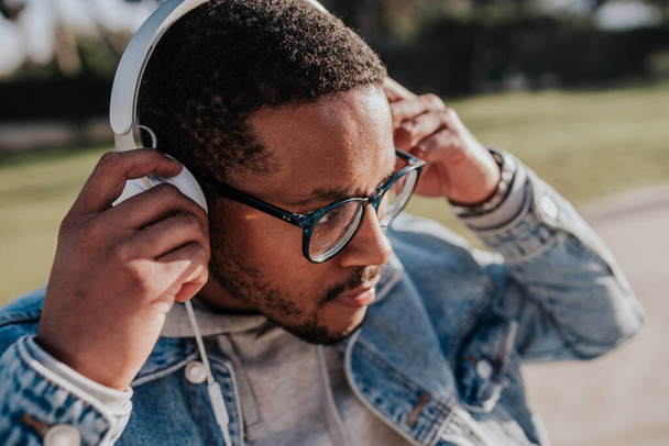 fekete fiú a parkban zenét hallgat fejhallgatóval - Fotó, kép