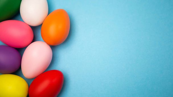 Płaski zestaw układanki dekorowane ręcznie malowane chaotycznie rozrzucone kolorowe jaja na niebieskim tle. Wesołych Świąt Wielkanocnych. Obraz z kopią wolnego miejsca na wiadomość tekstową - Zdjęcie, obraz