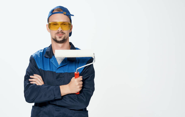 Mężczyzna naprawia żółte okulary i wałek do malowania ścian - Zdjęcie, obraz