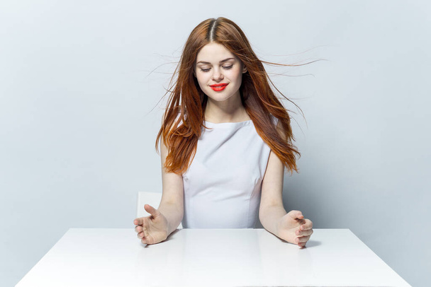 veselá žena sedí u stolu červené rty šarm gesto ruce studio - Fotografie, Obrázek