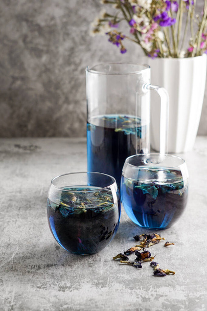 Cups of butterfly pea flower tea with  on grey background. Healthy concept - Фото, зображення