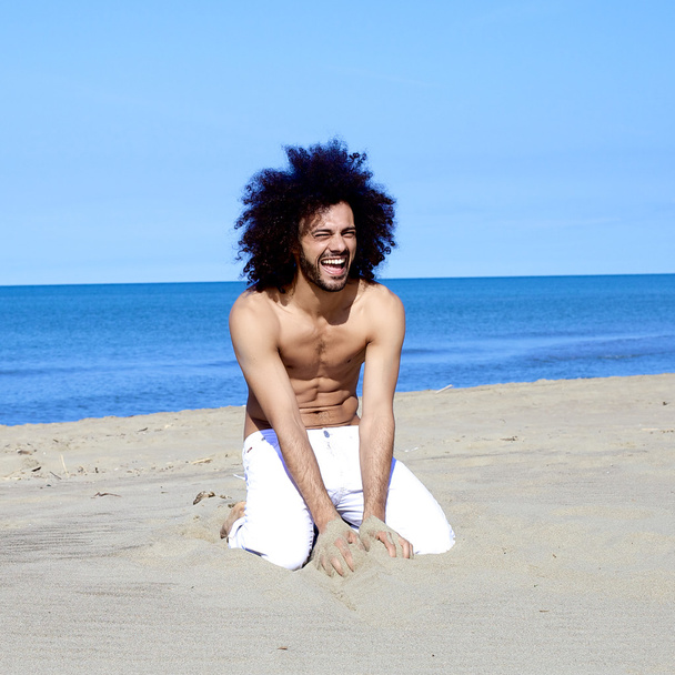 szép hűvös alkalmas férfi modell mosolyogva birtoklás móka-val homok, nyaralás - Fotó, kép