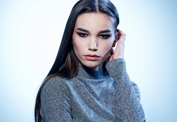 Retrato de uma mulher bonita em um suéter cinza morena maquiagem fundo leve - Foto, Imagem