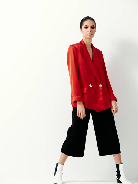 vrouw modieuze kleding rood jasje licht geïsoleerde achtergrond - Foto, afbeelding