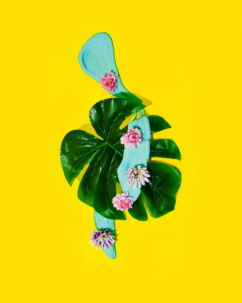 Monstera leaf with blue slime and flowers. Spring yellow background. - Foto, Imagem