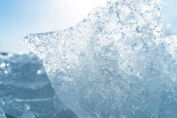Transparente brillante carámbanos de hielo claro primer plano chispeante en la orilla del lago salvaje congelado en la luz del atardecer. Frío invierno naturaleza fondo - Foto, Imagen