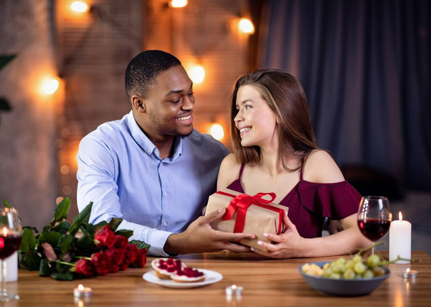 Cara afro-americano afetuoso surpreendendo sua namorada branca com presente romântico - Foto, Imagem