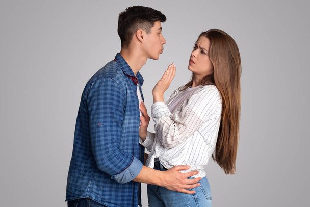 Mladý muž se snaží políbit rozrušenou dámu, žena nemá ráda obtěžování a nechce obtěžování - Fotografie, Obrázek