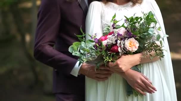 La novia y el novio están uno al lado del otro y sostienen un ramo - Metraje, vídeo
