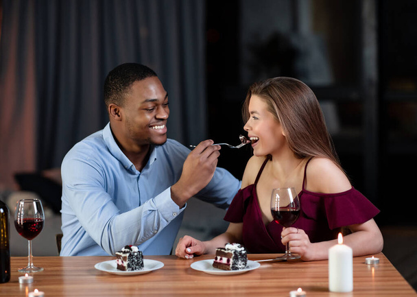 Kochający Afroamerykanin dzieli się deserem ze swoją białą dziewczyną, karmiąc ją - Zdjęcie, obraz