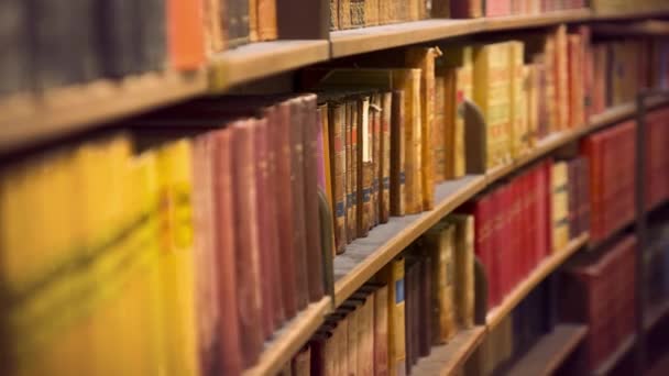 Camera beweegt langs gebogen planken met oude boeken in de bibliotheek - Video