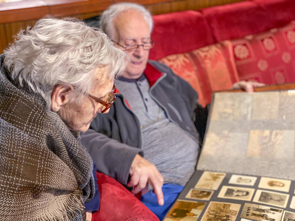 Ηλικιωμένοι ζευγάρι περιήγηση μέσα από παλιές φωτογραφίες. Μεγάλες αναμνήσεις φυλάσσονται στο άλμπουμ. - Φωτογραφία, εικόνα
