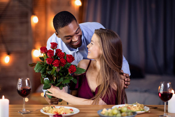 Amoroso afro-americano cara surpreendendo sua bela namorada com rosas buquê - Foto, Imagem