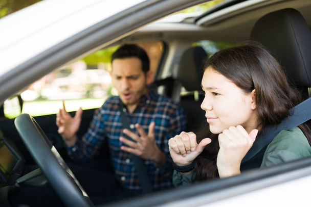 Stressed adolescent girl feeling scared and listening to her dad screaming because of her bad driving skills. Teenager girl about to cause a car accident for speeding - Photo, Image