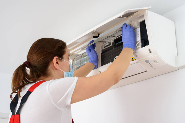 Nainen teknikko yllään kasvonaamio ja puhdistus ilmastointilaite - Valokuva, kuva
