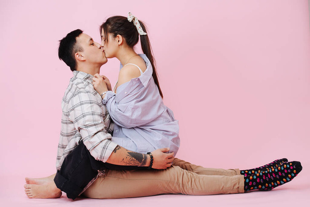 Young couple hugs and kissing on a pink background - Photo, image