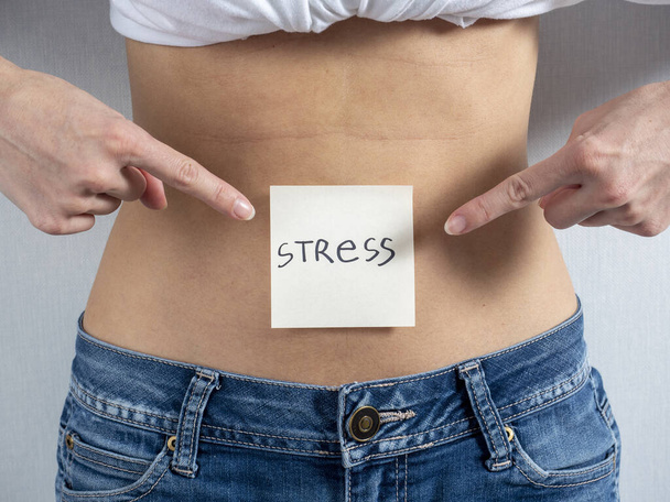 Paperi tarra sanat - Stressi on liitetty nuoren naisen paljaaseen vatsaan. Hän osoittaa sillä molemmin käsin. Raskauden käsite ja naisten asema yhteiskunnassa - Valokuva, kuva