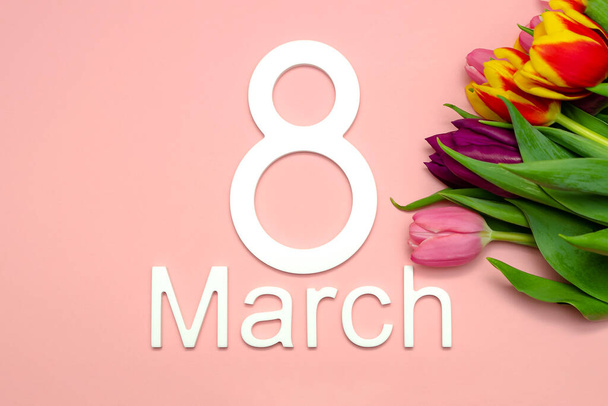 March 8, international womens day. Number eight against a background of tulips against a pink uniform background, place for text. - Photo, Image