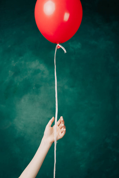 червона куля в руці на зеленому фоні летить крупним планом
 - Фото, зображення