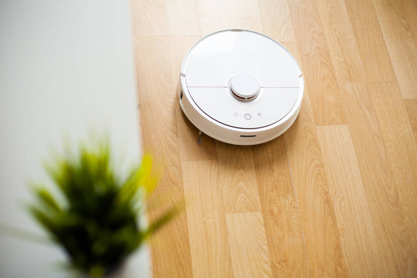 Staubsaugerroboter führen zu einer bestimmten Zeit die automatische Reinigung der Wohnung durch. Smart Home. - Foto, Bild