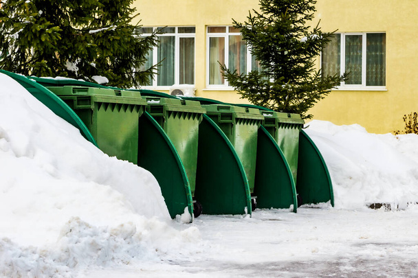 Bir apartmanın karlı avlusunda yeşil çöp tenekeleri - Fotoğraf, Görsel