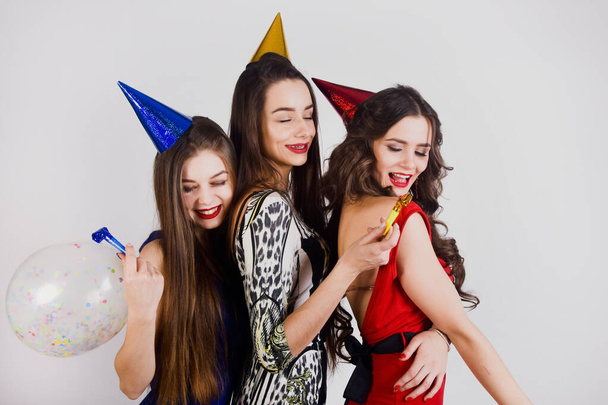 Crazy party time of three beautiful stylish women in elegant evening outfit celebrating , having fun, dancing smile on white background. Best friends girls in party cap on pink background.  - Photo, Image