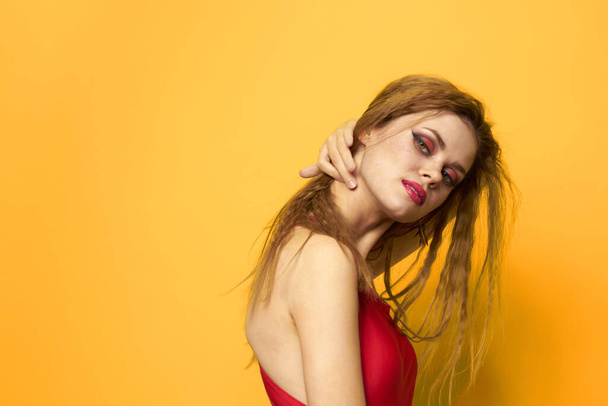 Mulher bonita cabelo ondulado tanque vermelho top moda estilo de vida cosméticos fundo amarelo - Foto, Imagem