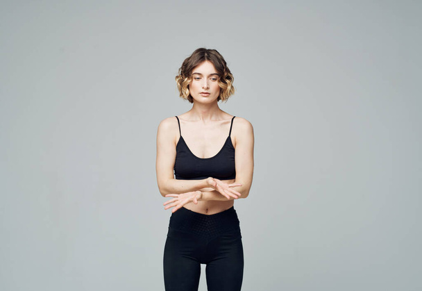 Woman in dark sportswear on gray background gesturing with hands cropped view - Foto, immagini