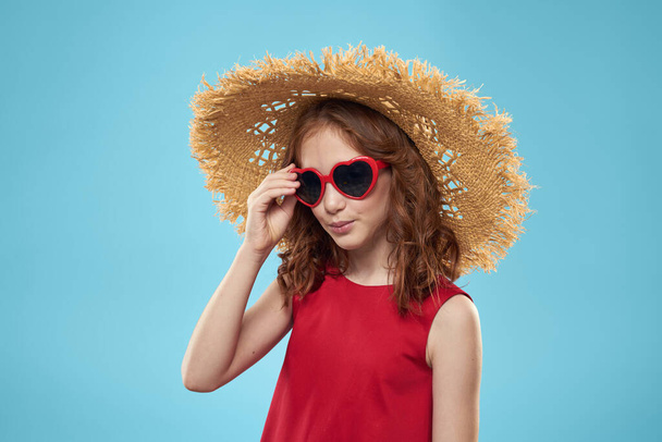 Κορίτσι σε μια παραλία Ψάθινο καπέλο σε γυαλιά ηλίου σγουρά μαλλιά διασκεδαστικό μπλε φόντο - Φωτογραφία, εικόνα