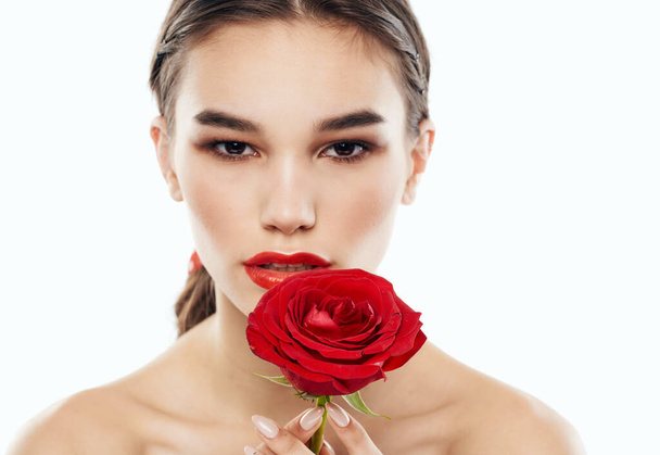 Portrait of romantic people with bare shoulders and a red flower in front of their eyes - Photo, Image