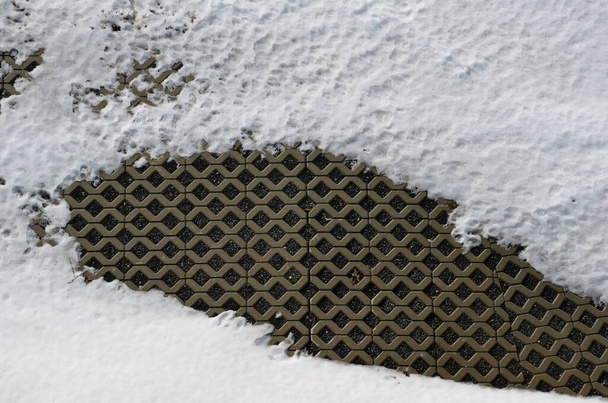草の舗装は、表面の強化と同時に、それらの草を可能にします。車の駐車場などの砂利でジョイントを埋めることもできます。雪に覆われた舗装のコンクリートタイプ - 写真・画像