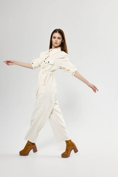 Woman in white overalls on a light background fashionable clothes shoes gestures with her hands - Φωτογραφία, εικόνα