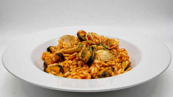 Вкусное ризотто из морепродуктов, Risotto ai frutti di mare, на белом блюде. - Фото, изображение