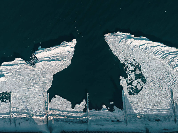 Balti-tenger fagyasztott tengerparttal. Jégtömbök és alakzatok lebegnek a tengerben. Drónlövés. téli táj. felülnézet - Fotó, kép