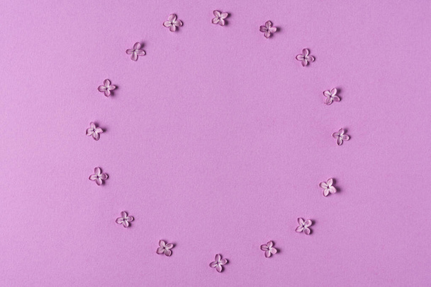 Marco hecho de flores de color lila primavera sobre fondo púrpura con espacio de copia. Composición floral. Acostado. Vista superior. Fondo de boda o vacaciones - Foto, imagen